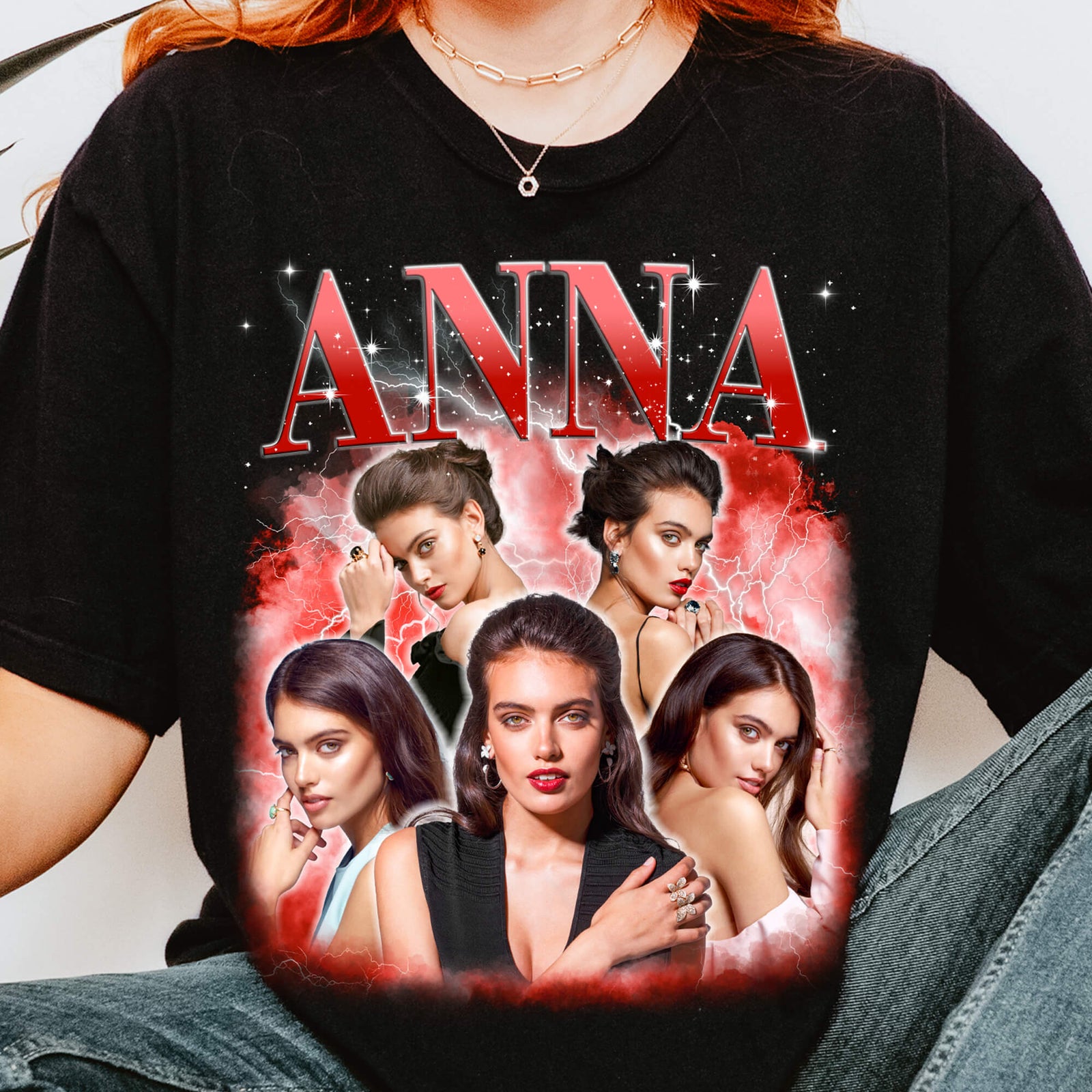 A black short-sleeve graphic T-shirt worn by a model, featuring the word 'ANNA' in large red letters above a collage of five portrait photos with red and white flame-like borders.