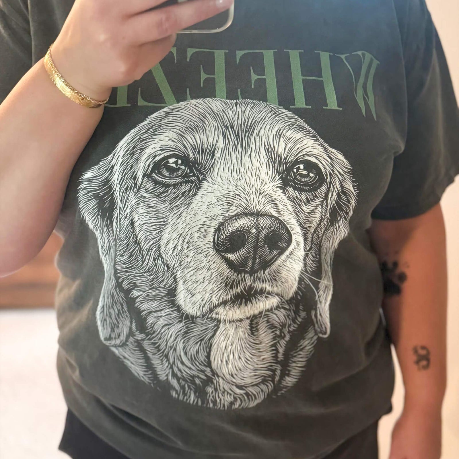 Mirror selfie showing a person in a faded charcoal T-shirt with an oversized white line-art portrait of a dog across the front.